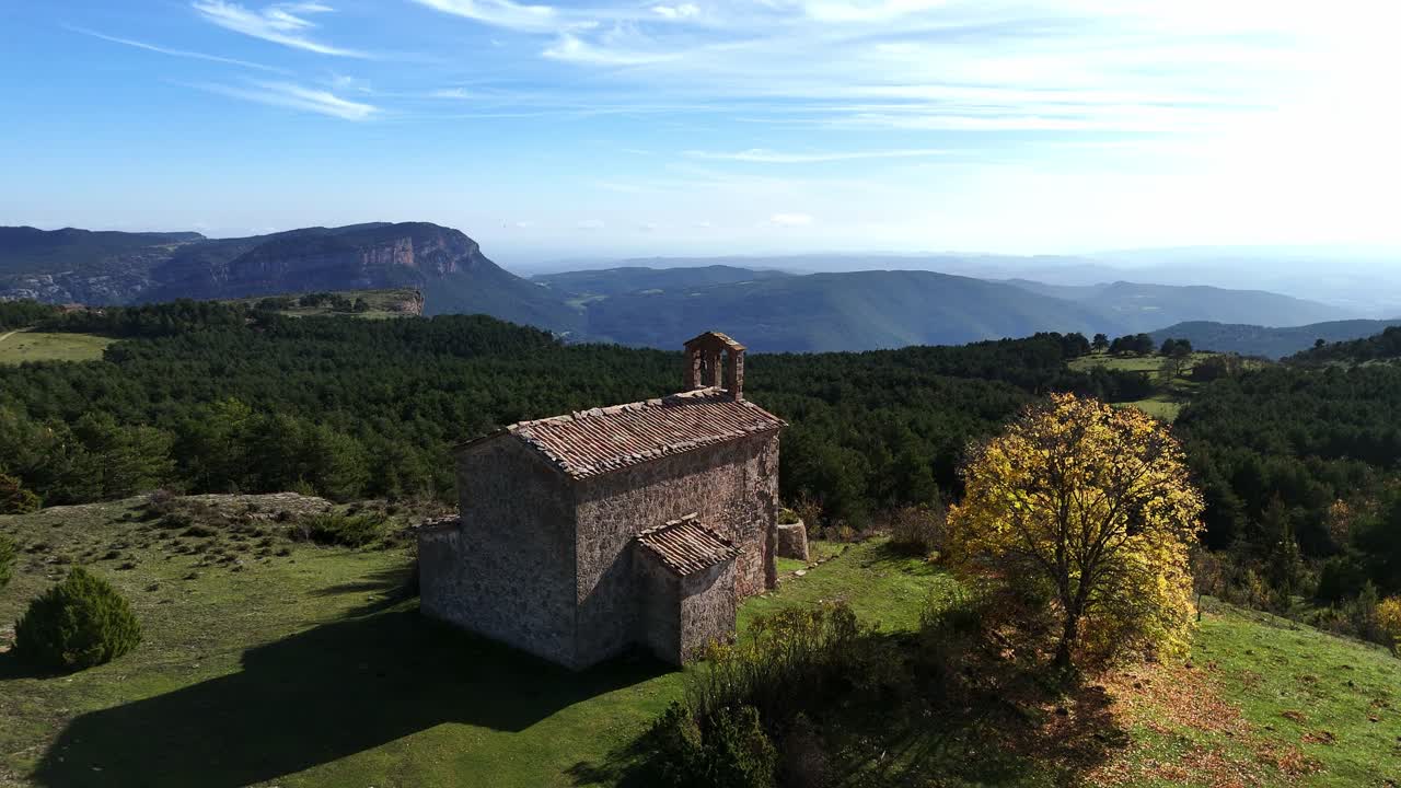 Una serena chiesa di montagna circondata da foreste e valli, con paesaggi mozzafiato e un cielo azzurro brillante in Catalogna.