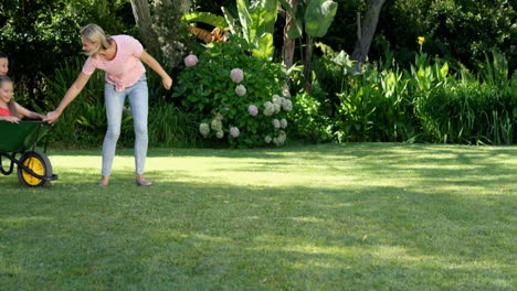 La-Familia-Feliz-Está-Jugando-Con-Carretilla-En-El-Jardín.