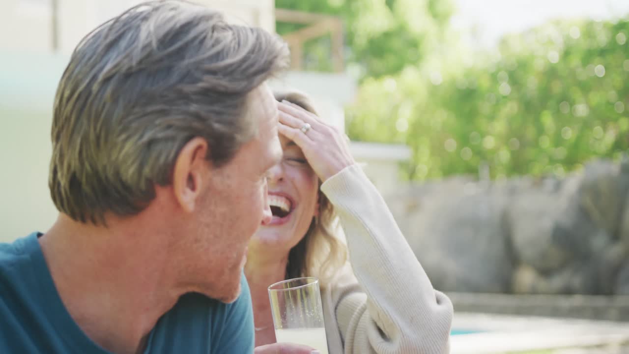 feliz pareja caucásica cenando y hablando en el jardín