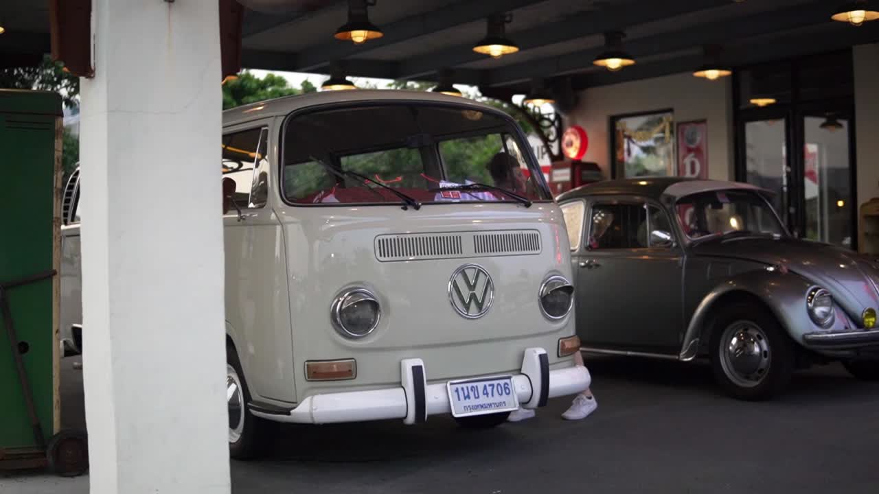 modelo femenina mirando coches antiguos clásicos de volkswagen en exhibición pública en el mercado nocturno rot fai en bangkok, tailandia