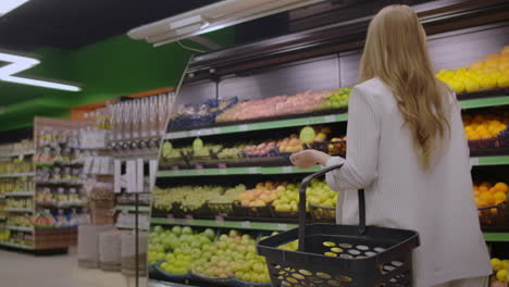 Back-view-Young-housewife-with-basket-shopping-at-the-grocery-store.-Cute-girl-goes-to-the-grocery-department-and-puts-in-the-basket.-Concept-purchase-shop-advertise-buyer-product-bakery