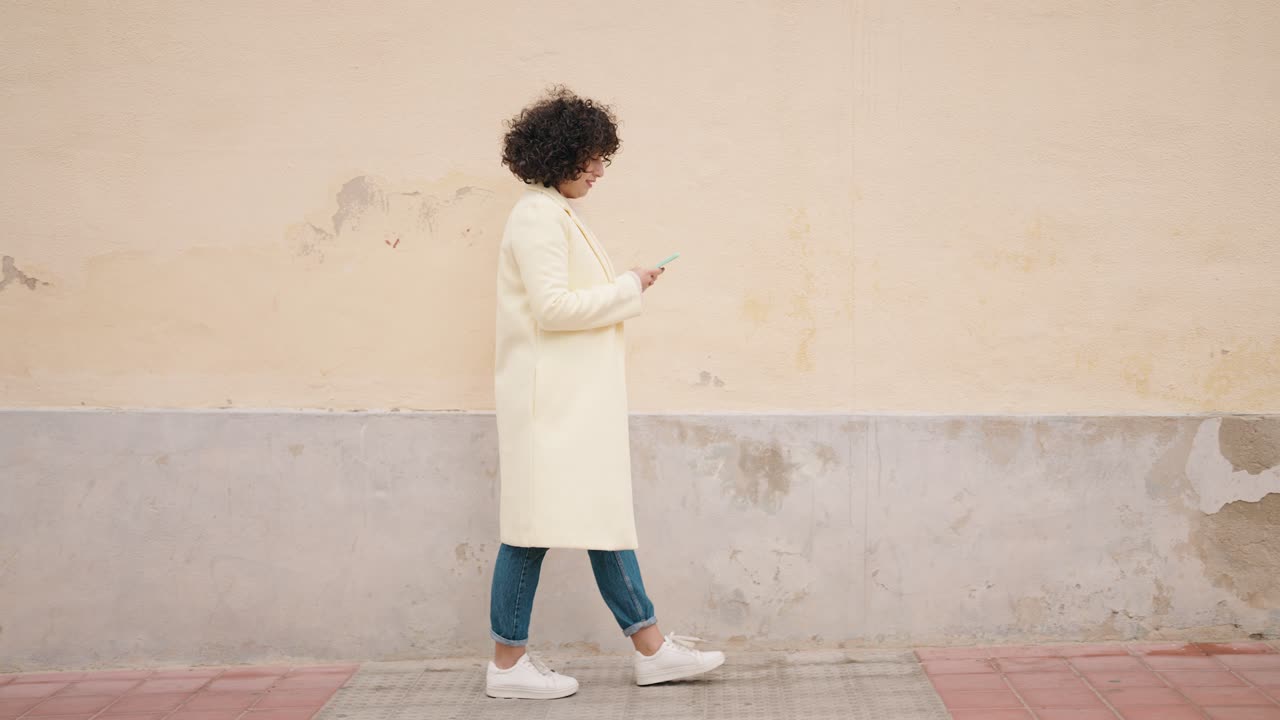 Young woman using smartphone walking at street