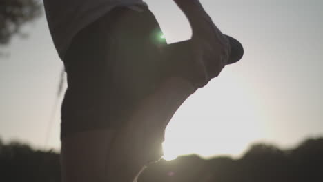 Close-Up-Shot-of-a-Young-Man-Stretching-Before-a-Run-In-The-Park-Whilst-Being-Silhouetted-By-The-Evening-Sun