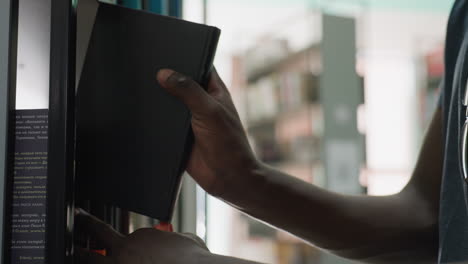 close up of person returning book to shelf in library, with sunlight streaming in and blurred background of bookshelves creating peaceful academic atmosphere in quiet study environment