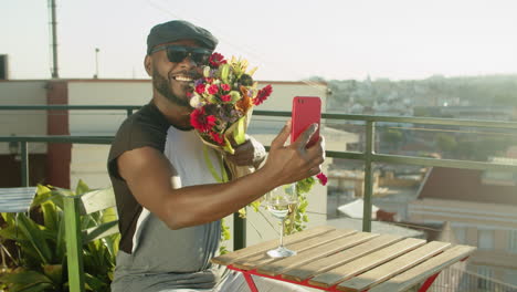 man having video call with boyfriend while waiting him in cafe and showing flowers