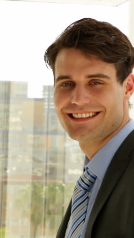 businessman looking out his window then turning to camera