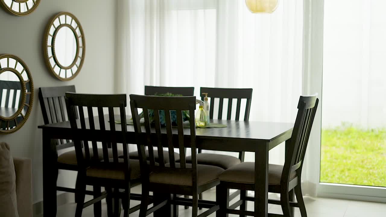 comedor con mesa, sillas y espejos junto a una ventana