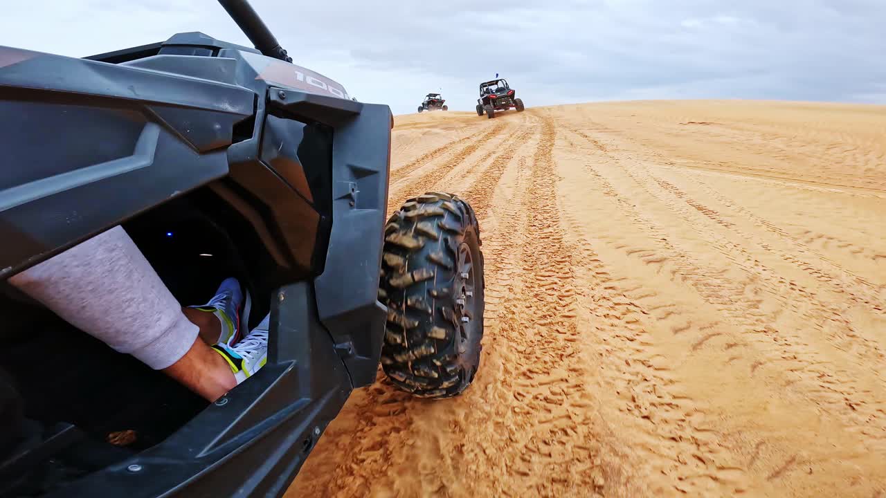 Powerful side angle shows buggy racing through soft sand on Dubai desert trails