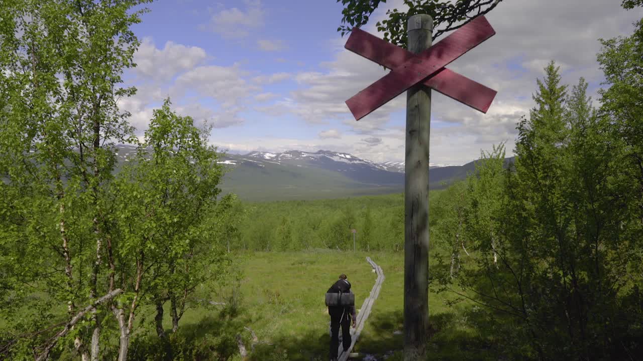 un excursionista se aleja de la cámara por un sendero sobre las montañas