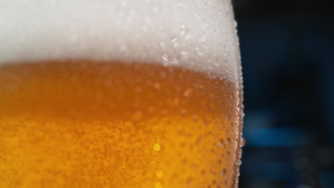 glass of beer with frothy foam and droplet of water running down in slow motion