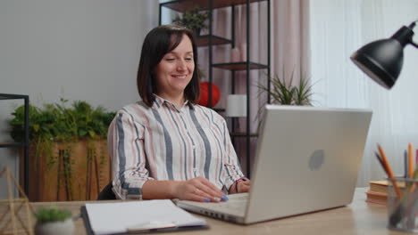mujer joven freelance en la oficina de casa haciendo llamadas de video por portátil conversación de chat, trabajando en línea