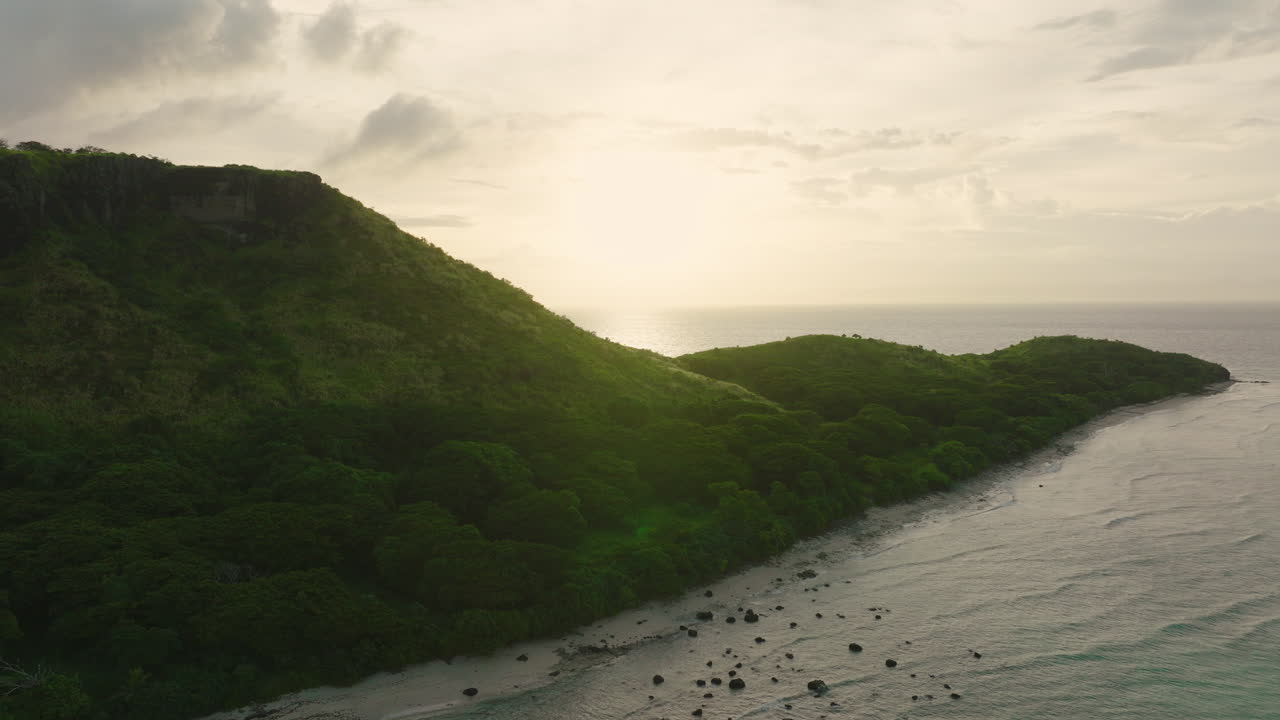 Hilly coastal terrain in moody light with ocean in background