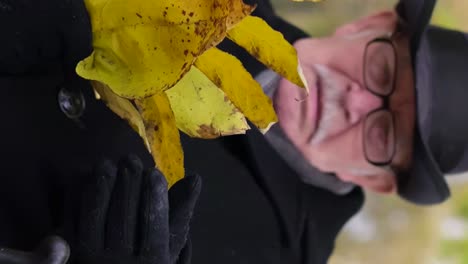 an old lonely man in a black coat and hat sits in an autumn park and holds yellow leaves an old lonely man in a black coat and hat sits in an autumn park and holds yellow leaves happy elderly people
