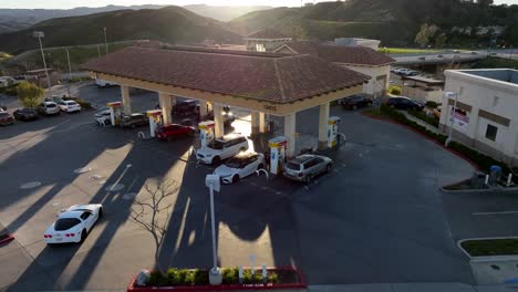 cars refueling at a gas station at sunset - ascending aerial view