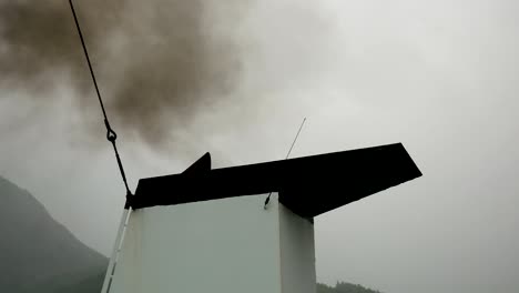 out of the ship pipe releases black smoke into the air and pollution it