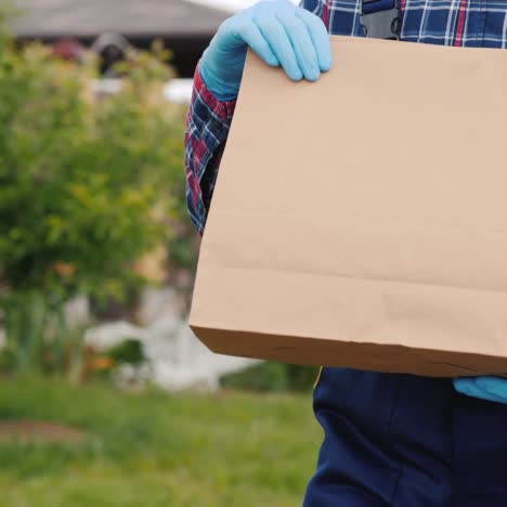 Un-Empleado-Del-Servicio-De-Entrega-Lleva-Bolsas-De-Comida-A-La-Casa-Del-Cliente