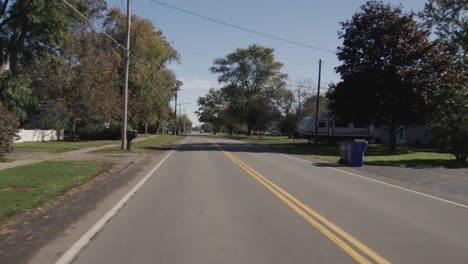 driving straight on a flat road in a typical american agricultural region. rear view