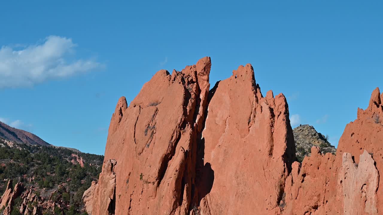 Crisp drone shot of rugged red rock formations at Garden of the Gods with blue skies and scattered clouds in Colorado Springs