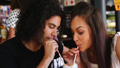 couple drinking smoothie together with straw in pub