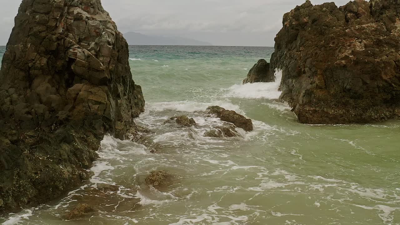 Scogli oceanici con onde al rallentatore che si infrangono nelle acque turchesi di Banbanon Beach a Surigao Del Norte, Filippine