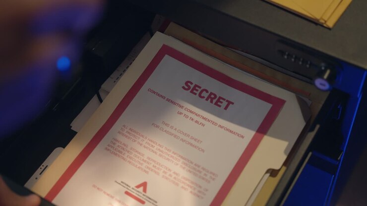 Secret agent, spy or thief holding a flash light opening a drawer and taking out classified files while looking around cautiously. Espionage, intelligence, top secret, surveillance, undercover.