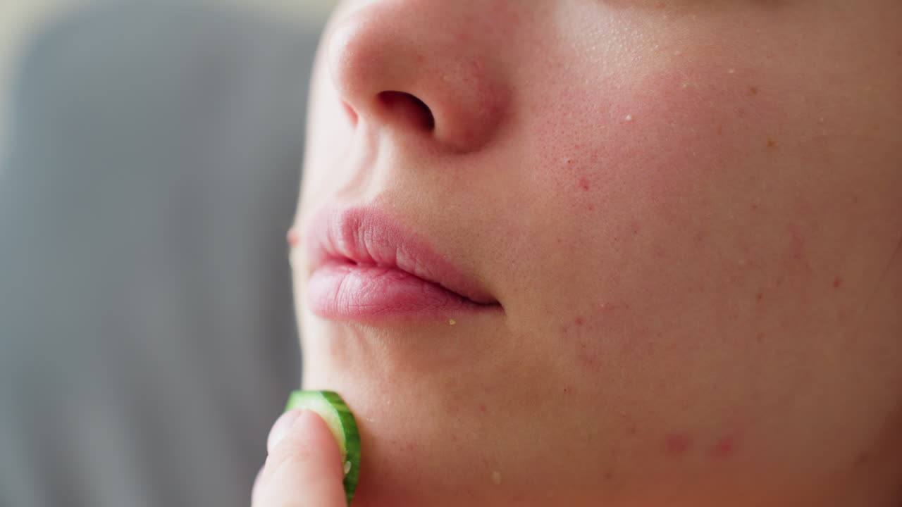 Extreme close-up of woman gently massaging cucumber on chin during skincare routine, highlighting natural skin texture and self-care moment, focused on facial rejuvenation, hydration