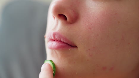 extreme close-up of woman gently massaging cucumber on chin during skincare routine, highlighting natural skin texture and self-care moment, focused on facial rejuvenation, hydration