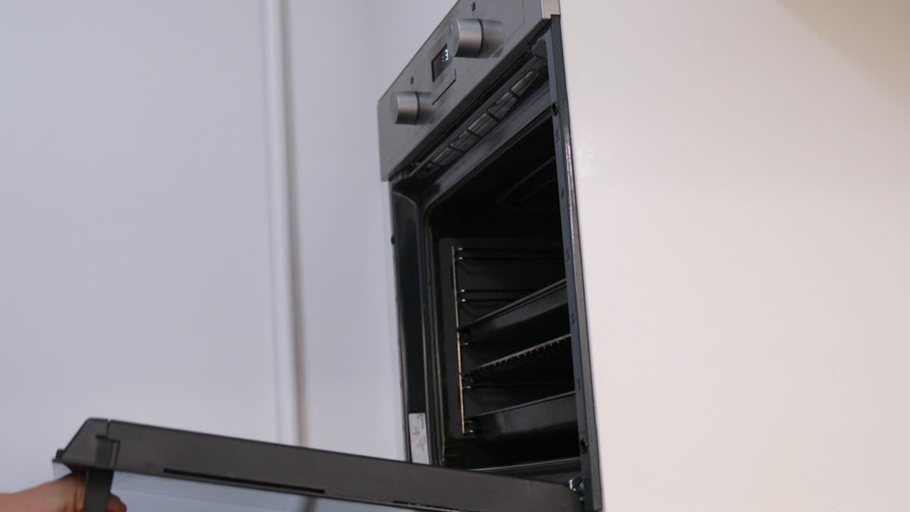 toma casual estática de un hombre abriendo un kirtoven moderno y sacando la bandeja de cocina