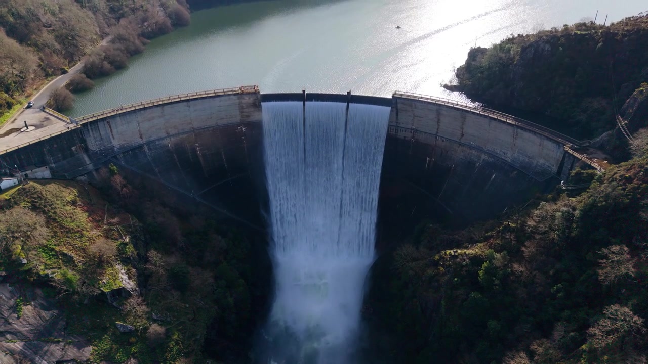 Veden virtaus hidastettuna Encoro do Eumen tekoaltaan ylivuotoputkesta Galiciassa, Espanjassa. Ilmakuva, jossa kamera loittonee ja nousee.