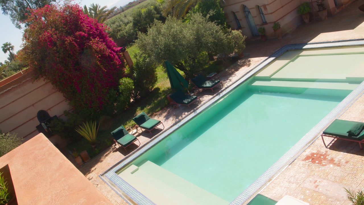 Sunny villa courtyard with swimming pool, lounge chairs, and lush garden plants