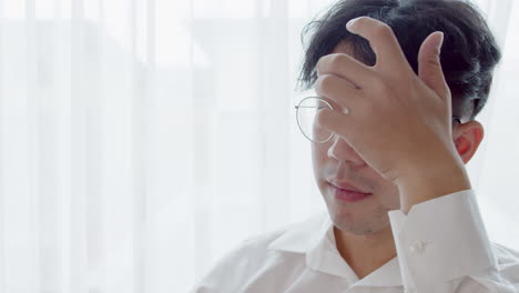 안경을 쓰고 건강한 좋은 머리를 가진 아시아 남자가 카메라를 바라보고 머리를 정리하여 자신을 망쳤습니다.