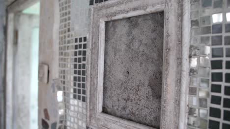 A-close-up-shot-of-an-old-and-dirty-wooden-frame-inside-a-creepy-and-abandoned-house-with-glass-mosaic