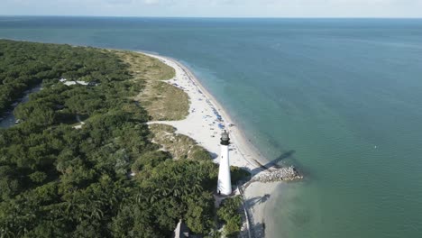 Drone-Vuela-Por-Encima-De-La-Antena-Del-Faro-De-Cape-Florida,-Extremo-Sur-De-Key-Biscayne-En-El-Condado-De-Miami-Dade,-Florida,-EE.UU.,-Con-Una-Playa-Tropical-De-Arena-Blanca