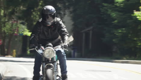 Motociclista-Con-Chaqueta-De-Cuero-Cabalgando-Por-Un-Camino-Arbolado