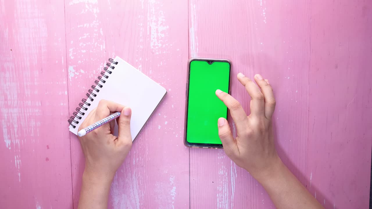 Person taking notes and using a phone