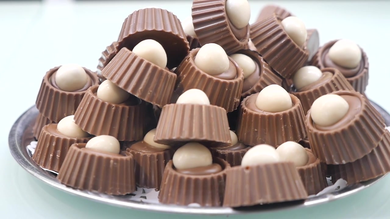 Mucchio di dolcetti al cioccolato al latte con ripieno di cioccolato bianco su un piatto.