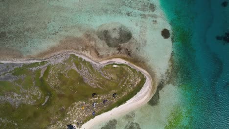 Aerial-tilt-up-view-of-a-vibrant-coral-barrier-with-boats-and-island-coast