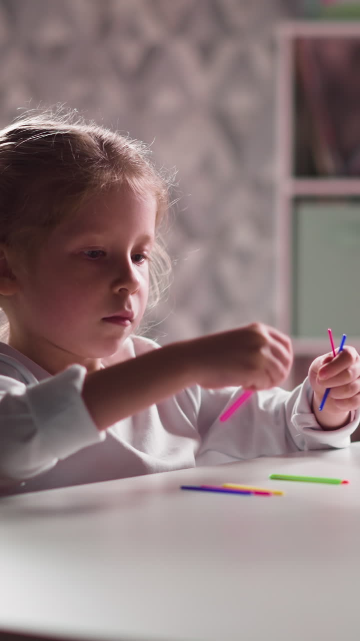 Concentrated little girl student with plaits puts small colorful sticks learning to count at mental arithmetic class in room closeup slow motion