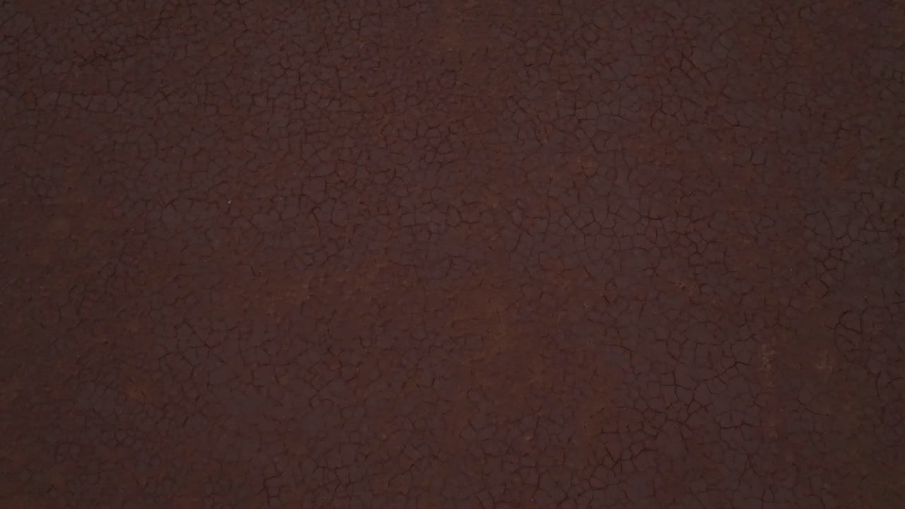 clip de avión no tripulado que muestra una amplia extensión de suelo desértico agrietado, inclinándose hacia el horizonte y el horizonte