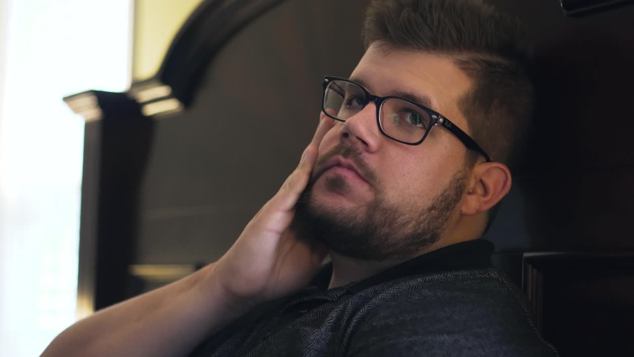 Mann gnir seg i ansiktet og sjekker klokken sin mens han tar en pause fra å spille videospill med vennene sine.