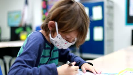 Mientras-Los-Niños-Regresan-A-La-Escuela-Durante-El-Virus-De-La-Corona,-La-Pandemia-De-19,-Un-Niño-Con-Una-Máscara-Se-Sienta-En-Su-Escritorio-Y-Comienza-A-Completar-El-Trabajo-Escolar