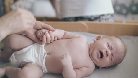 newborn baby lies on table and pediatrician performs massage