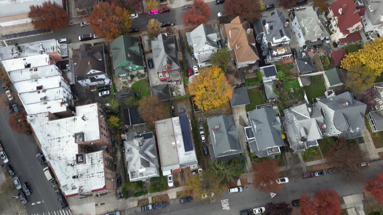 Filmato aereo che mostra isolati alberati di Brooklyn con auto parcheggiate e case residenziali. Colori autunnali intensi dominano la scena con forti motivi simmetrici dall'alto
