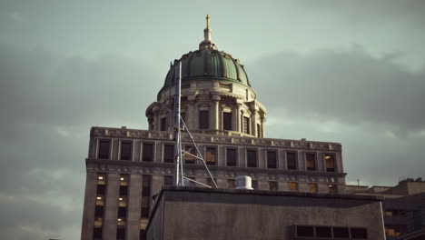 un primer plano de un edificio alto con una cúpula en la parte superior, contra un cielo nublado.