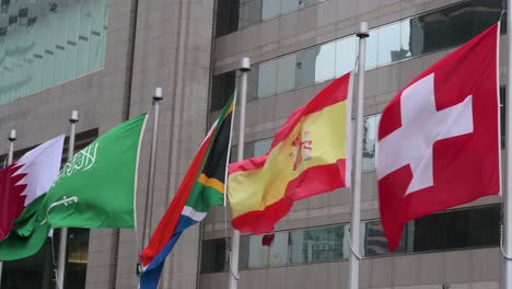 Banderas-Nacionales-De-Suiza,-España,-Sudáfrica,-Arabia-Saudita-Y-Jordania-Se-Ven-Ondeando-En-El-Viento-En-Hong-Kong