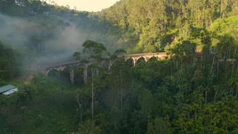 Aufsteigende-Drohnenaufnahme-Der-Neun-Bögen-Brücke-An-Einem-Sonnigen-Und-Nebligen-Morgen-In-Ella,-Sri-Lanka