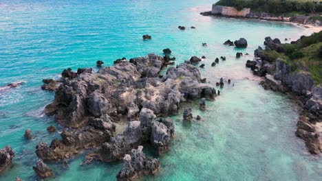 aerial view of sharp pointy rocks in turquoise water by tropical island