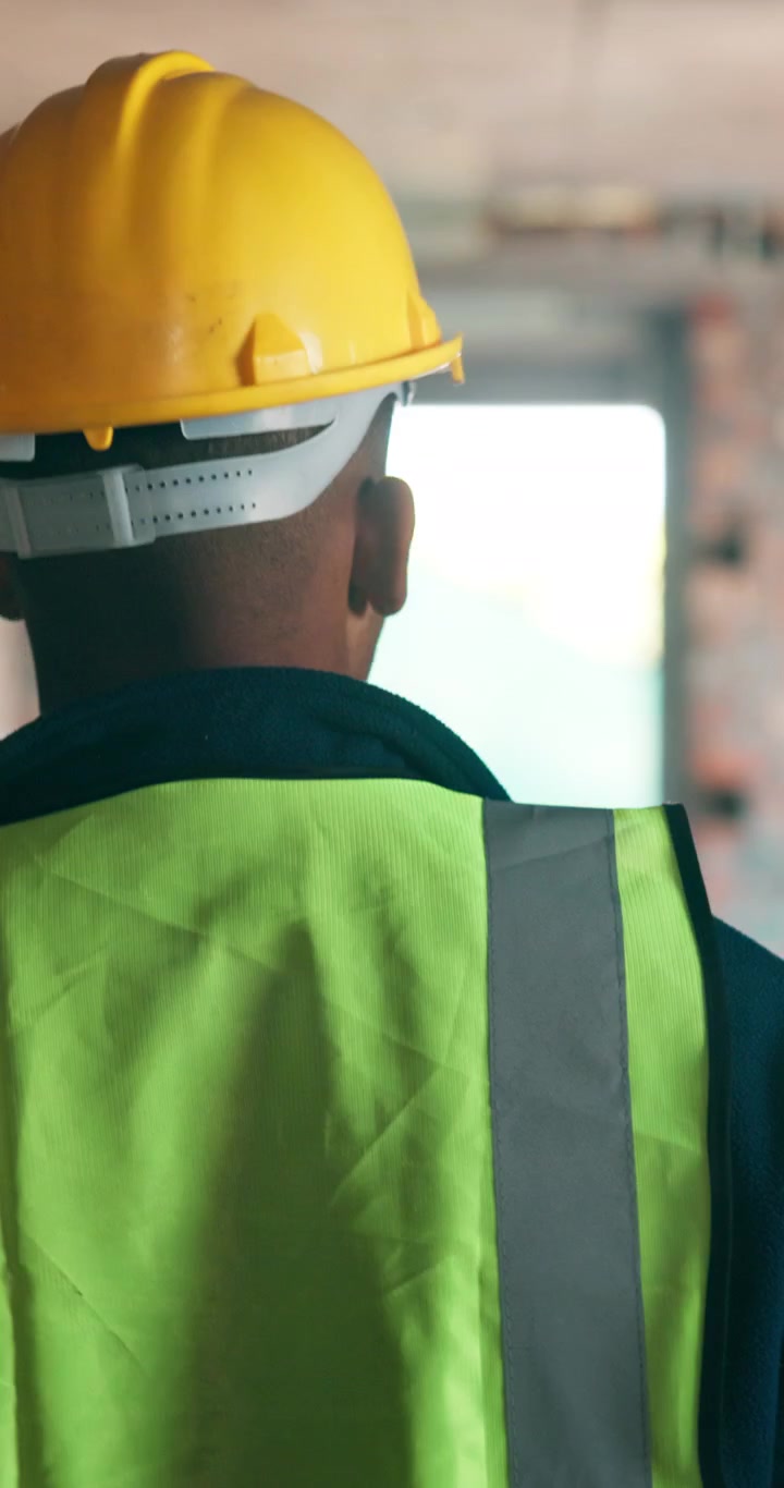 Operaio edile con equipaggiamento di sicurezza che ispeziona un cantiere