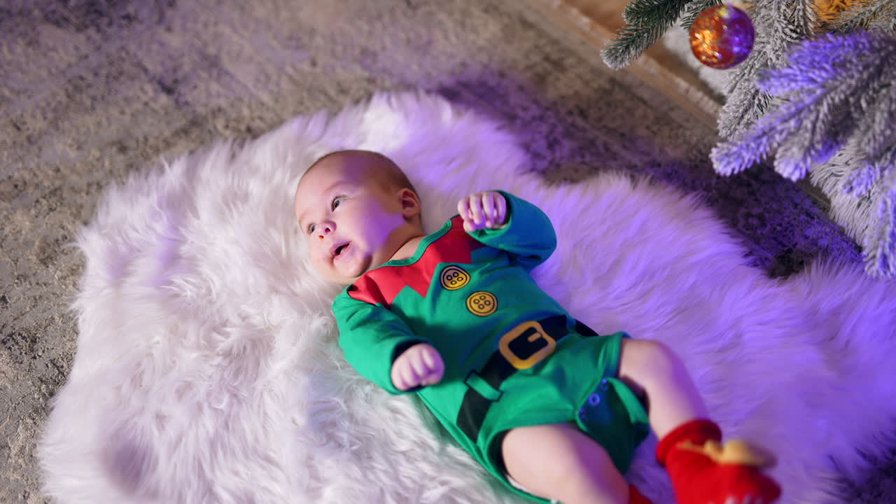 Cute newborn baby in gnome costume lies on a fluffy plaid. Adorable little child at Christmas tree.