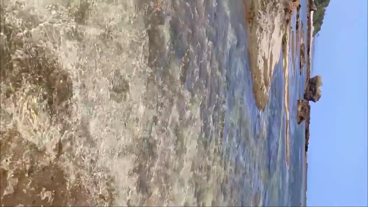 Vista verticale delle acque limpide del mare sulla spiaggia di Sayangheulang a Garut, Giava Occidentale, Indonesia. Rallentatore.